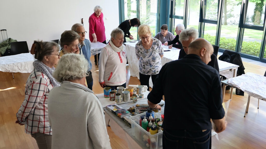 Senioren und Seniorinnen leben sich kreativ mit Pinsel und Farben aus.